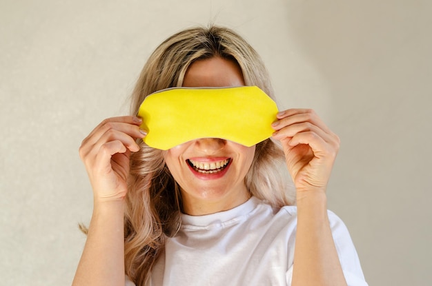 Young blonde woman with sleeping mask having fun and relaxing at home Wellness and chilling concept quality of sleep good night insomnia relaxation healthy night sleep