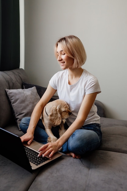 young blonde woman with a spaniel sitting at a laptop blogger working on the internet home office