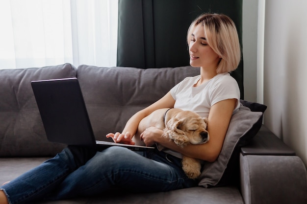 young blonde woman with a spaniel sitting at a laptop blogger working on the internet home office