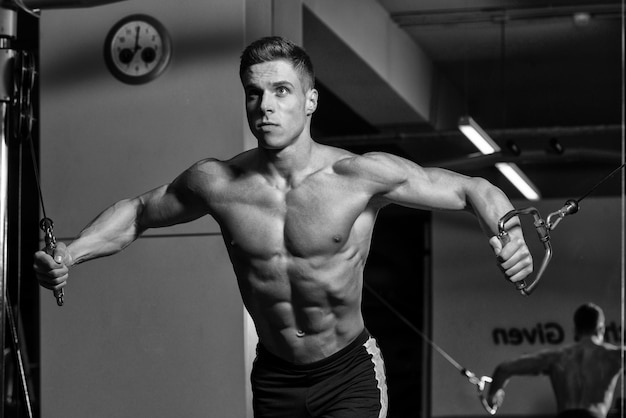 Young Bodybuilder Is Working On His Chest With Cable Crossover In A Dark Gym