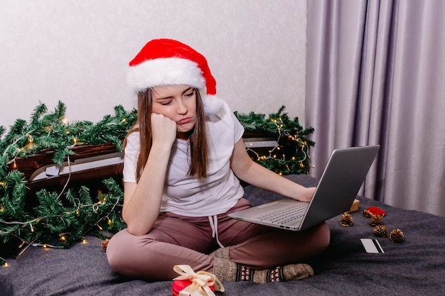 A young bored woman shopping online for Christmas