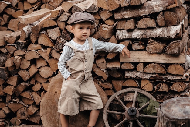 A young boy in a cap next to a woodpile in a natural landscape Closeup Gives the picture an authentic mood Vintage Rustic