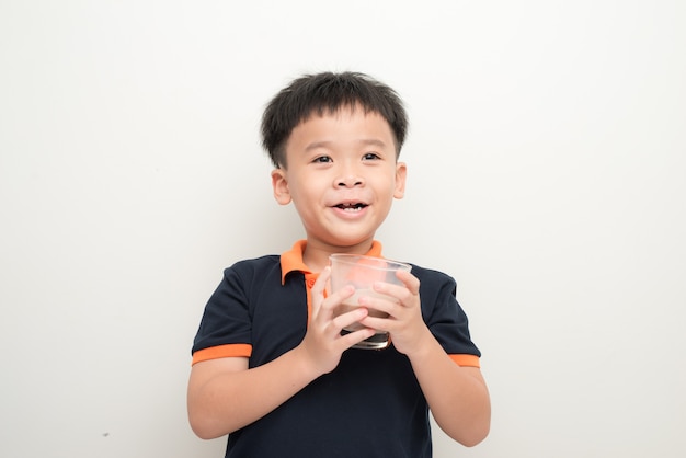 Young boy drinking chocolate milk isolated on white wall background.