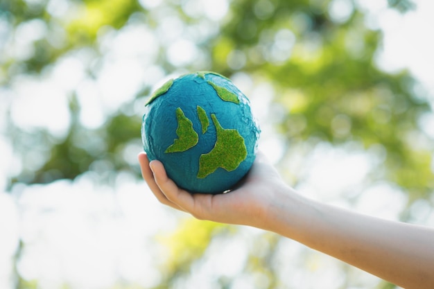 Photo young boy hand holding planet earth globe at natural park background gyre