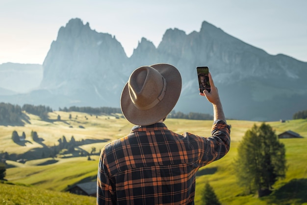 young boy in hat and plaid shirt taking a selfie in Alpe di Siusi Dolomites