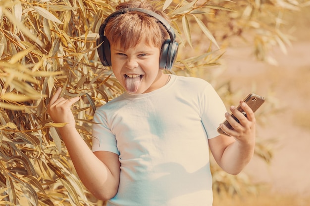 Young boy in headphones with smartphone listens to music in the park