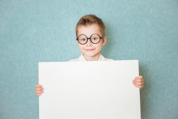 Young boy holding white blank board on blue background