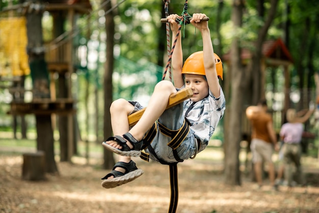 A young boy is hanging on the line in the rope park Sports entertainment for a child active rest