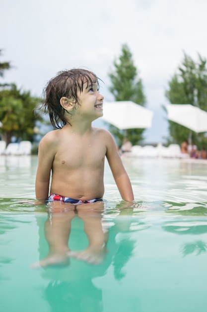 Young boy kid child splashing in swimming pool having fun leisure activity