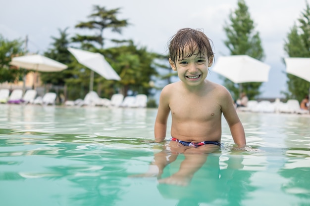 Young boy kid child splashing in swimming pool having fun leisure activity