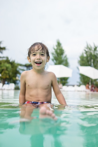 Young boy kid child splashing in swimming pool having fun leisure activity