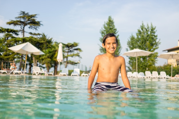 Young boy kid child splashing in swimming pool having fun leisure activity