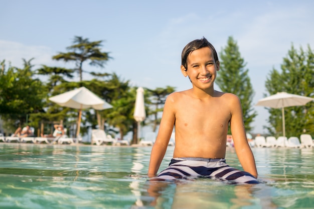 Young boy kid child splashing in swimming pool having fun leisure activity