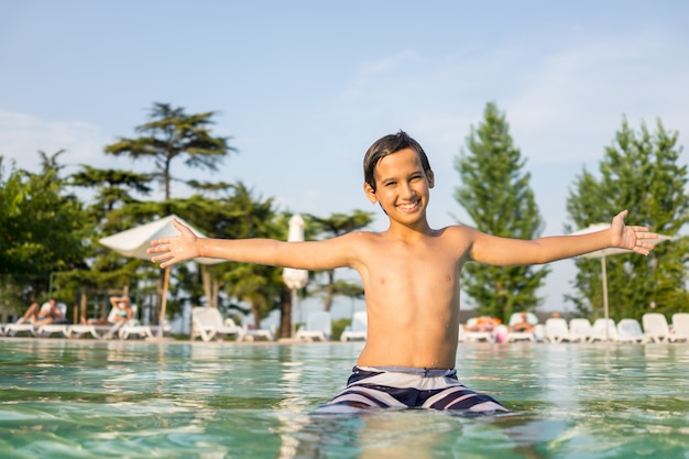 Young boy kid child splashing in swimming pool having fun leisure activity