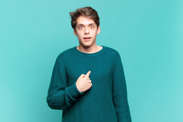 Young boy looking shocked and surprised with mouth wide open, pointing to self