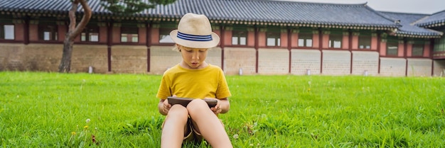 Young boy outdoors on the grass at backyard using his tablet computer educating and playing banner