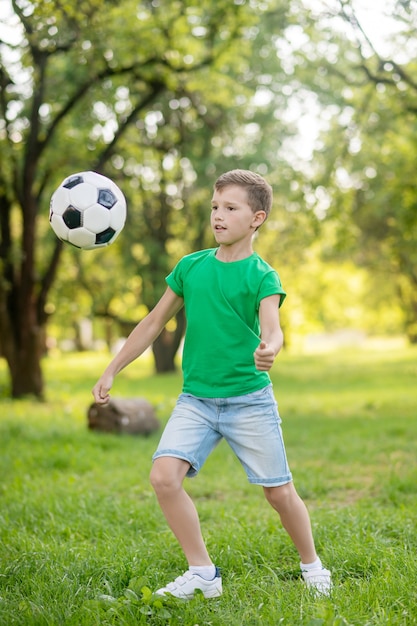 Young boy playing soccer ball in park