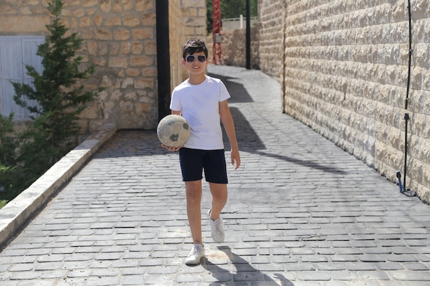 Young boy playing with a soccer ball In one Traditional Street in old Village summer background