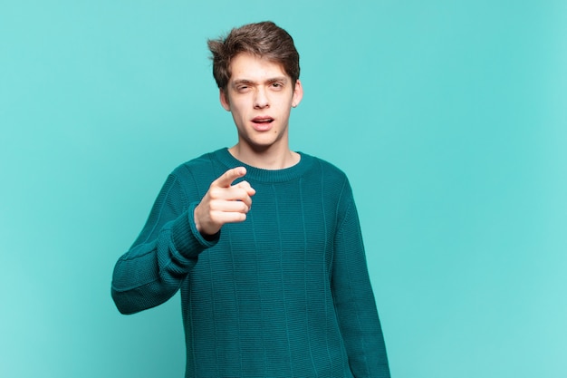 Young boy pointing at camera with an angry aggressive expression looking like a furious, crazy boss