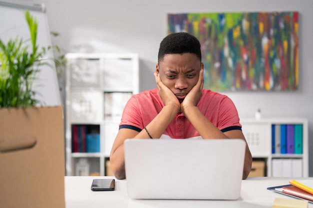 Young boy sits slumped in front of computer props hands under face bad news losing money overwork