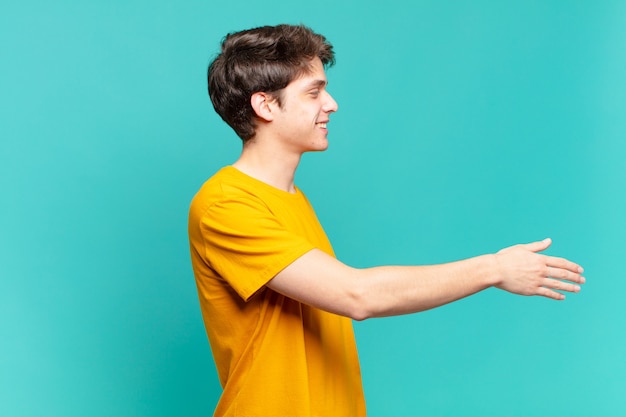 Photo young boy smiling, greeting you and offering a hand shake to close a successful deal, cooperation concept