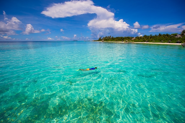 Young boy snorkeling in tropical turquoise ocean