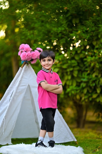 a young boy stands in front of a display of pink flowers