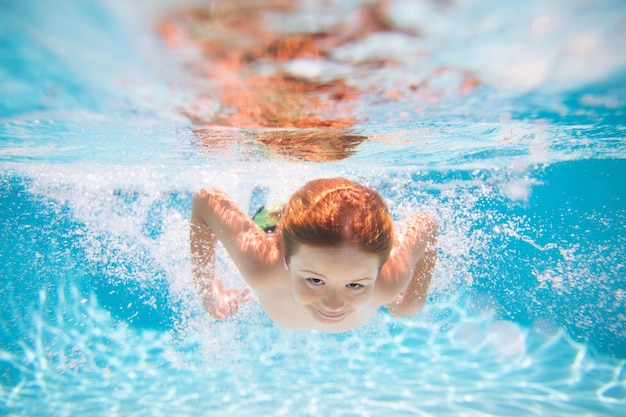 Young boy swim and dive underwater under water portrait in swim pool child boy diving into a swimmin