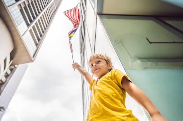 Young boy tourist with the flag of Malaysia near the skyscrapers Traveling with kids concept