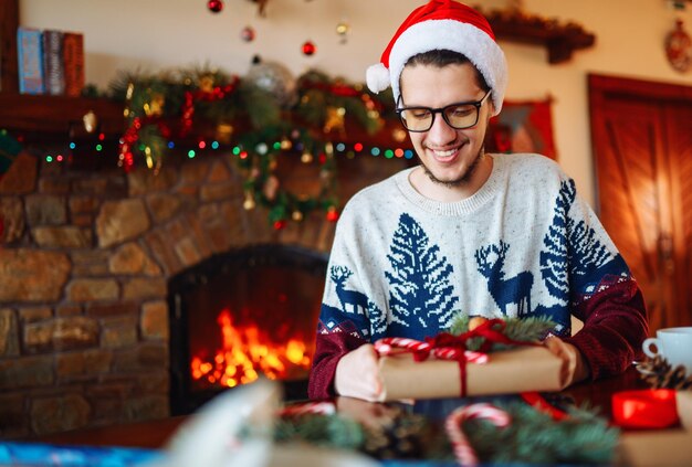 Young boy Tying Ribbon on Christmas Present New Year's mood blurred lights hearth fire in background