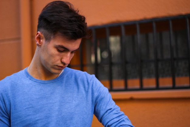 Young boy with blue polo shirt waiting on orange background on the street