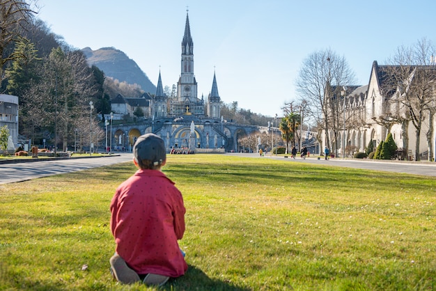 Young boy with the cathedral-sanctuary of Lourdes (France)