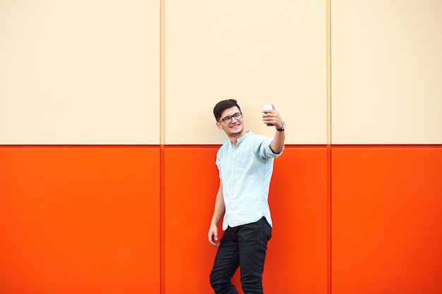 Young boy with eyeglasses taking a selfie in the street