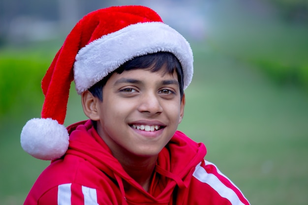 A young boy with Santa claus cap, smilling and lookin at the camera during Christmas time 