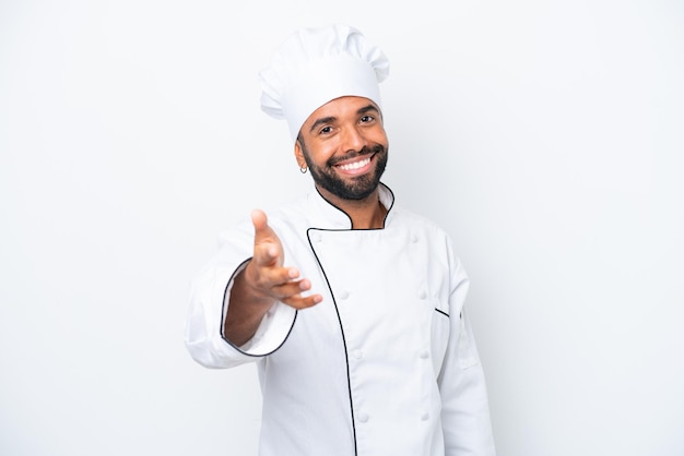 Young Brazilian chef man isolated on white background shaking hands for closing a good deal