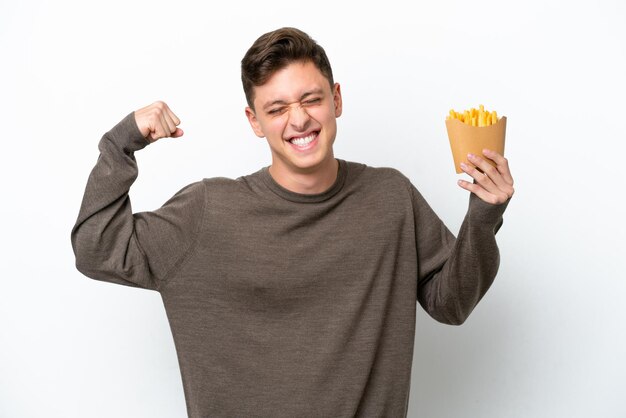 Young Brazilian man holding fried chips isolated on white background doing strong gesture