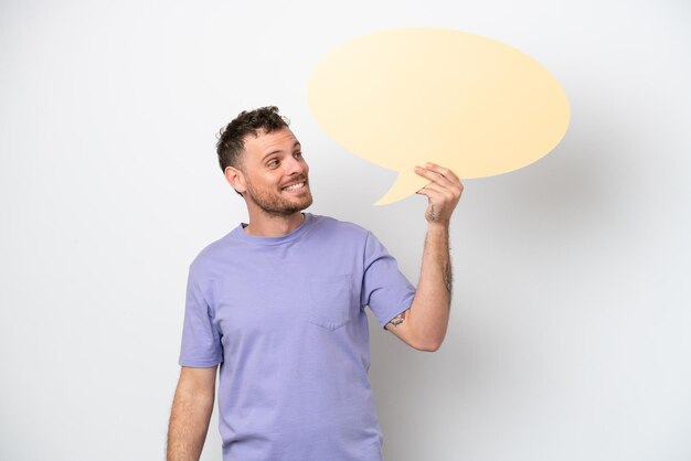 Young Brazilian man isolated on white background holding an empty speech bubble