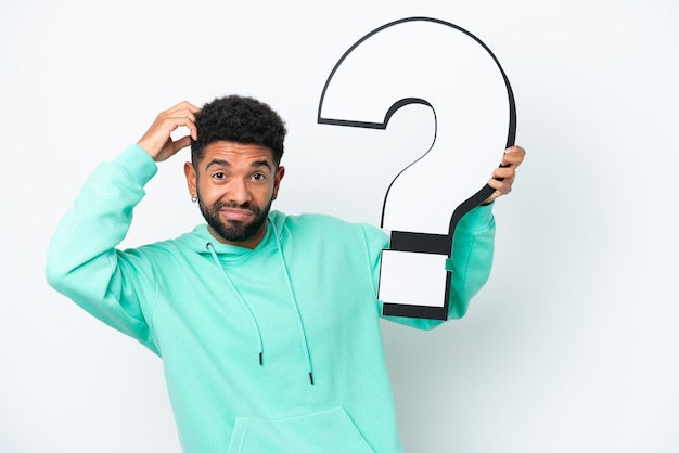 Young Brazilian man isolated on white background holding a question mark icon and having doubts