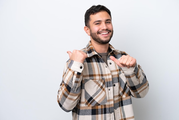 Young Brazilian man isolated on white background pointing to the side to present a product