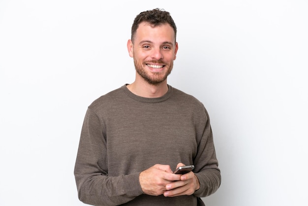 Young Brazilian man isolated on white background sending a message with the mobile