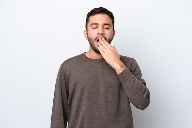 Young Brazilian man isolated on white background yawning and covering wide open mouth with hand