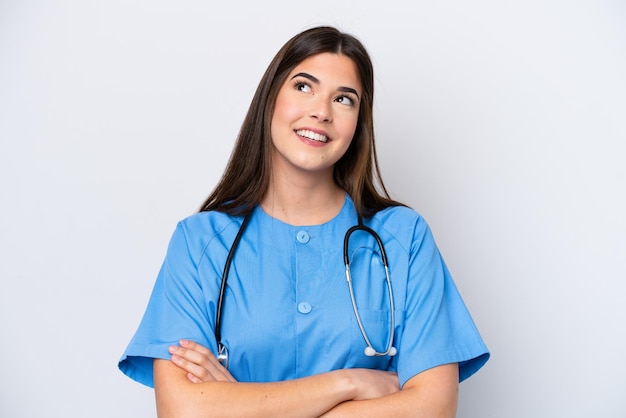 Young Brazilian nurse woman isolated on white background looking up while smiling