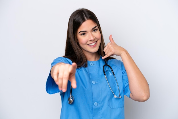 Young Brazilian nurse woman isolated on white background making phone gesture and pointing front