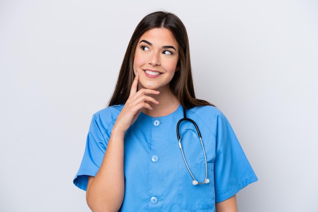 Young Brazilian nurse woman isolated on white background thinking an idea while looking up