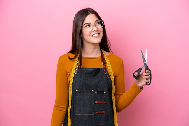 Young Brazilian seamstress woman isolated on pink background thinking an idea while looking up