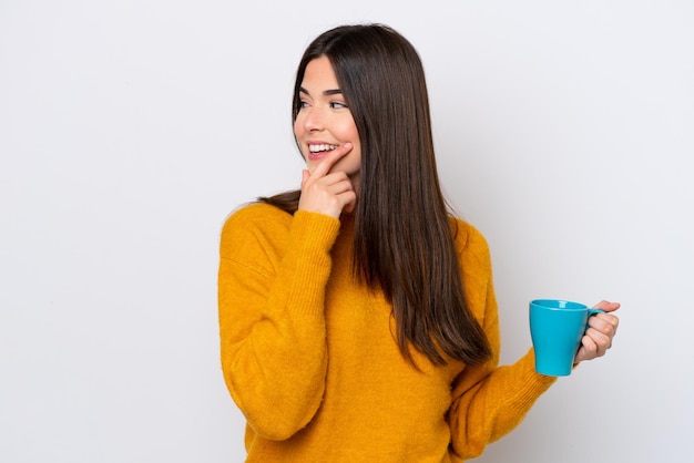 Young Brazilian woman holding cup of coffee isolated on white background thinking an idea and looking side