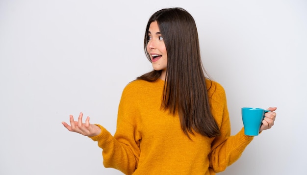 Young Brazilian woman holding cup of coffee isolated on white background with surprise facial expression