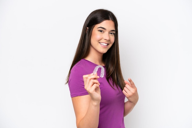 Young Brazilian woman holding invisible braces isolated on white background and pointing it