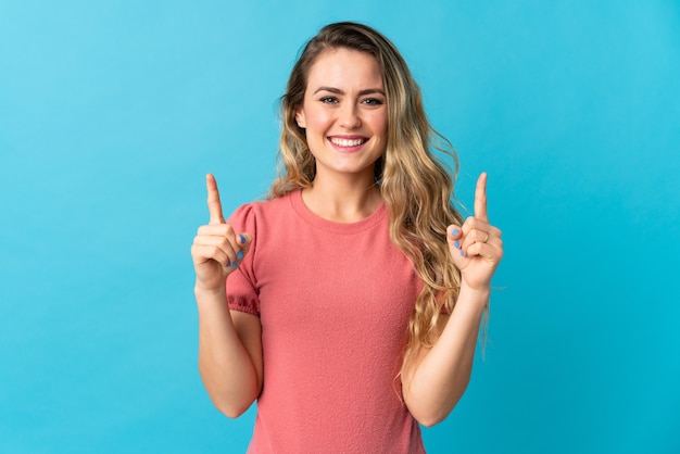 Young Brazilian woman isolated on blue background pointing up a great idea