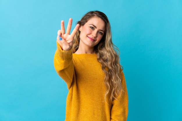 Young Brazilian woman isolated on blue happy and counting three with fingers